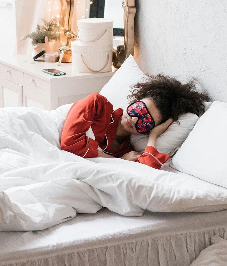 person laying in bed with sleep mask on