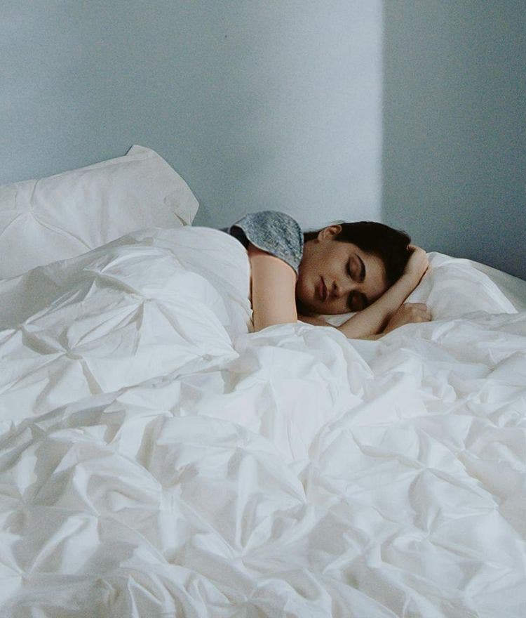 person sleeping in a bed with white bedding