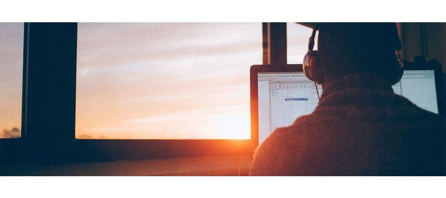 College student working on a laptop as the sun goes down