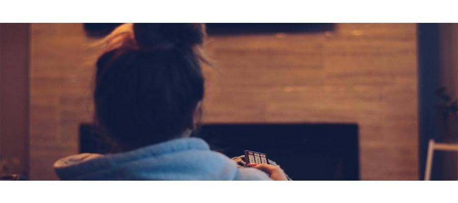 Woman with messy bun watching TV late at night