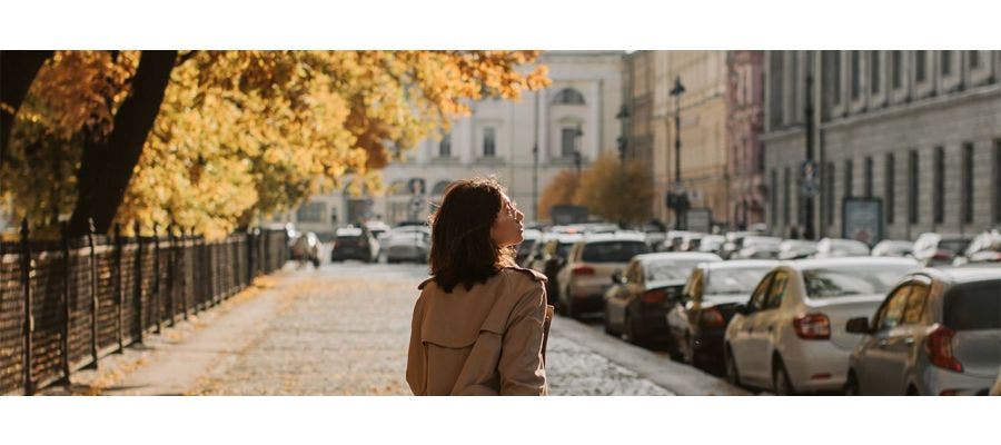 Woman in a long jacket, walking down the street on a windy fall day