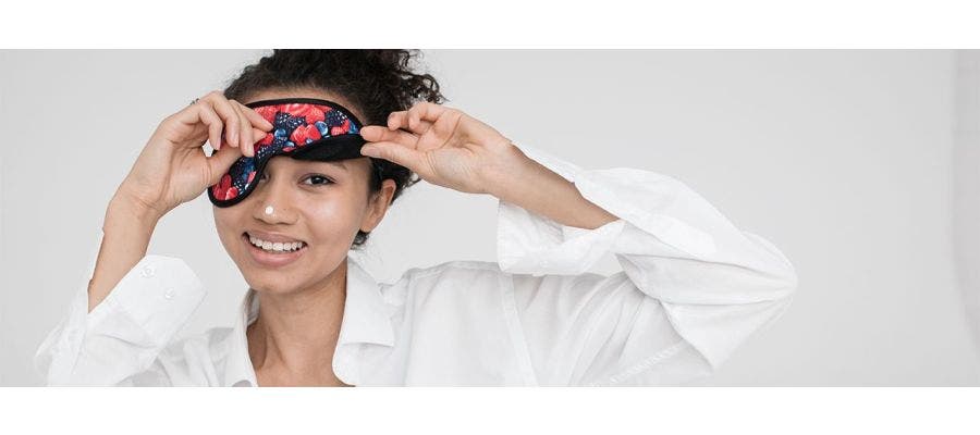 Woman wearing a sleep mask and pimple patch as self care