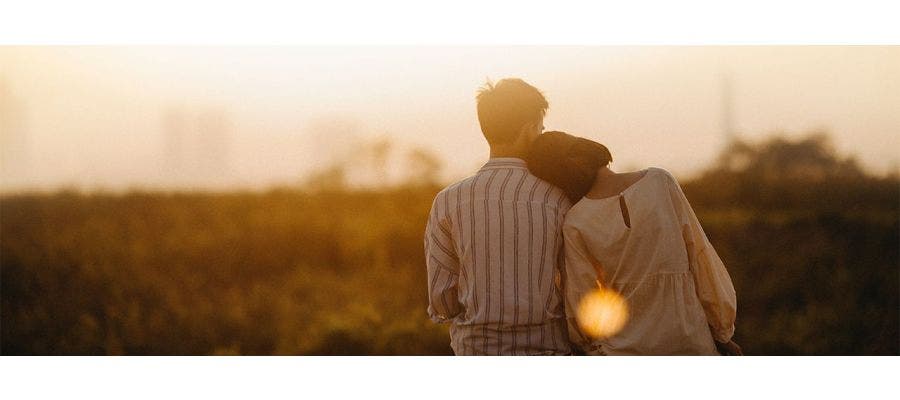 Couple snuggling outdoors and watching the sunset for Valentine's Day