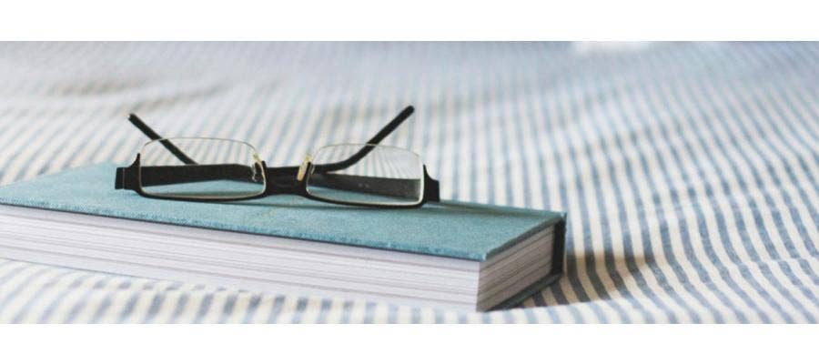 book and glasses on bed