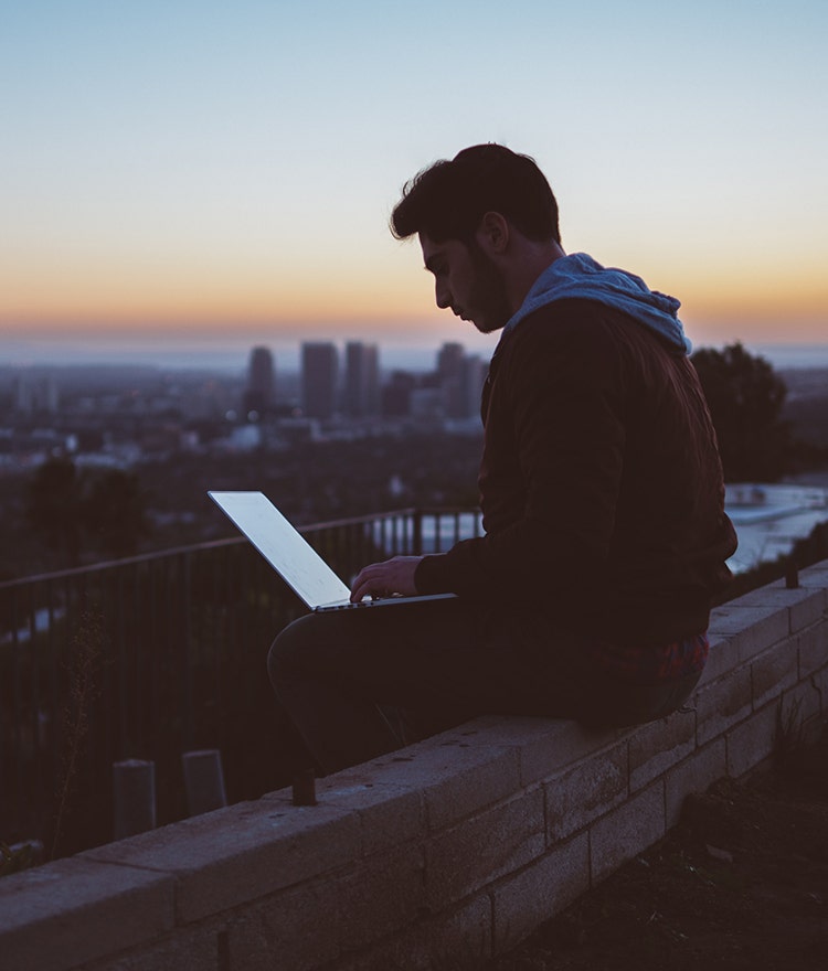 College student working on a laptop outdoors after sunset