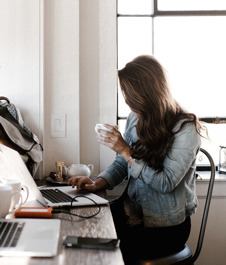 Young woman drinking coffee and working the day after an all-nighter