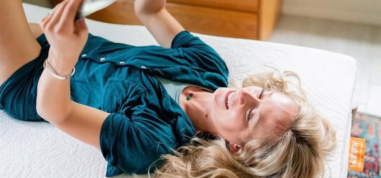 Woman lying on her back and reading on a Happsy organic mattress