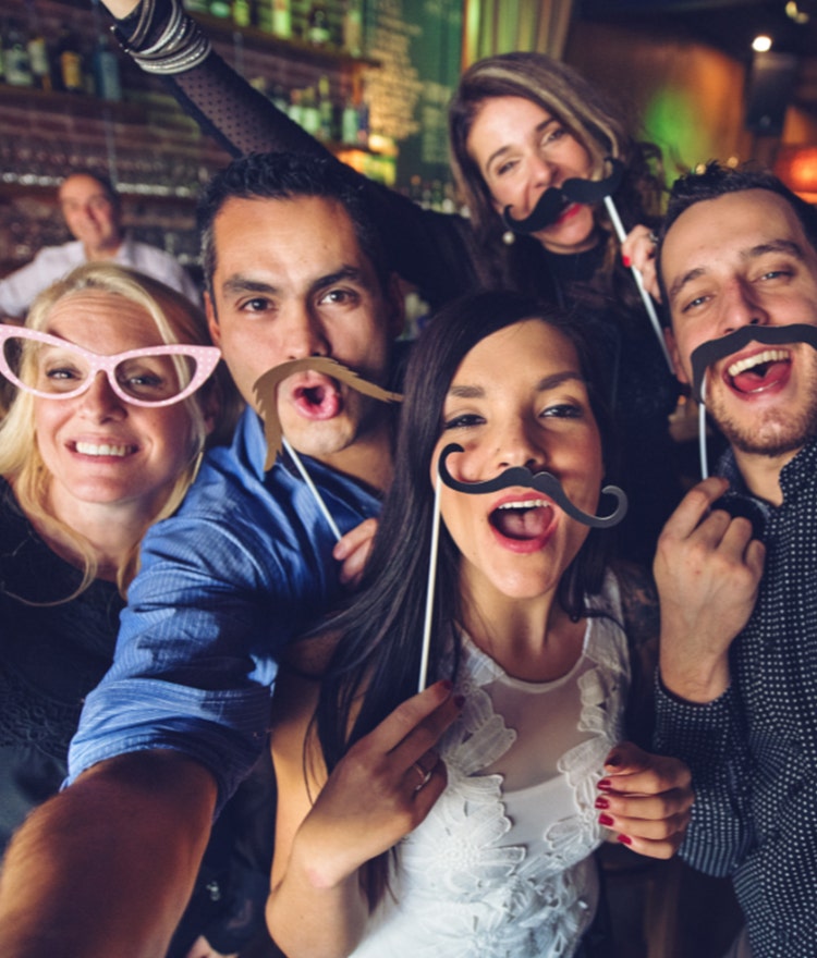 Friends using fun photo booth party props