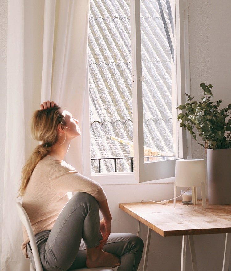 Woman suffering from seasonal depression, sitting near a window