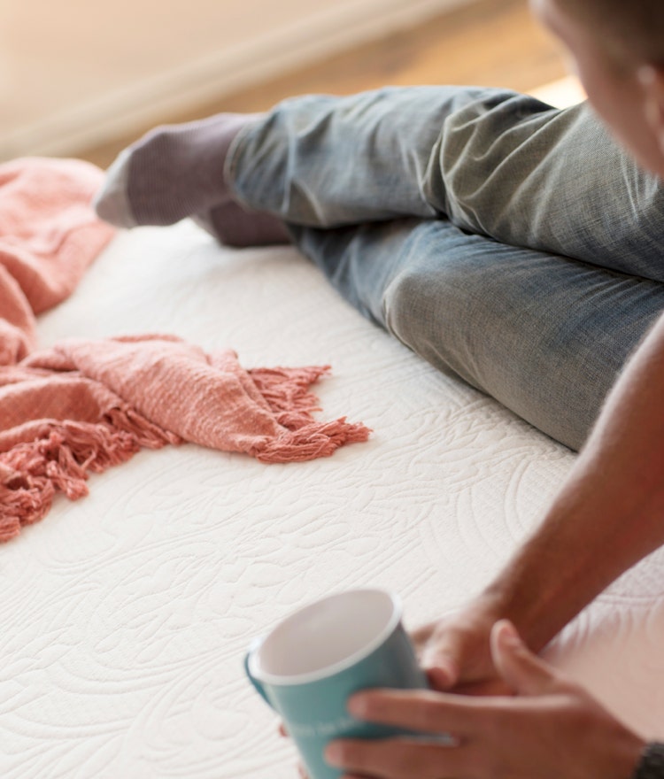 Young man relaxing on a Happsy mattress with a cup of coffee