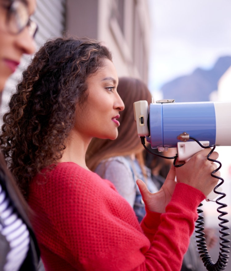 Woman in a crowd speaking into a megaphone 