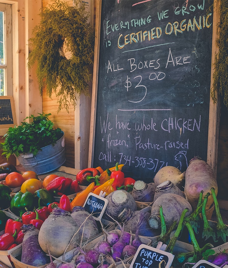 Farmer's market stand with frsh vegetables and chalk pricing board