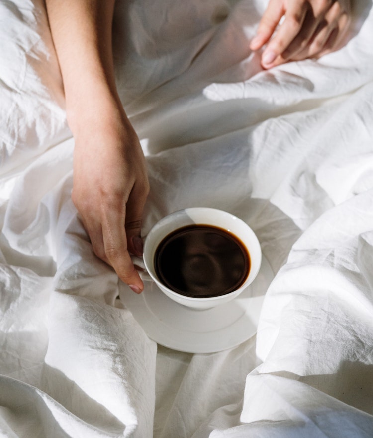 Person drinking coffee in bed