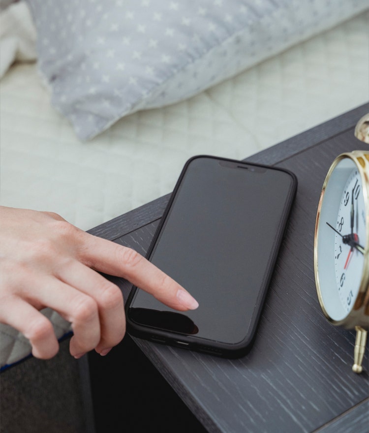 Woman's hand powering down her smartphone on the nightstand