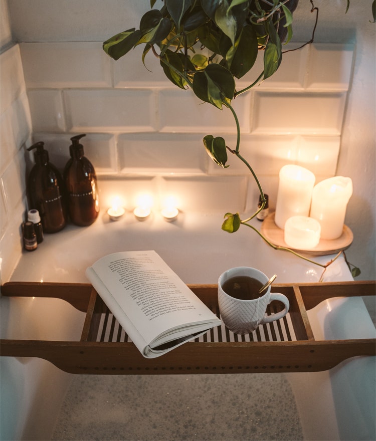 Relaxing bath set up with candles and a book and tea nearby