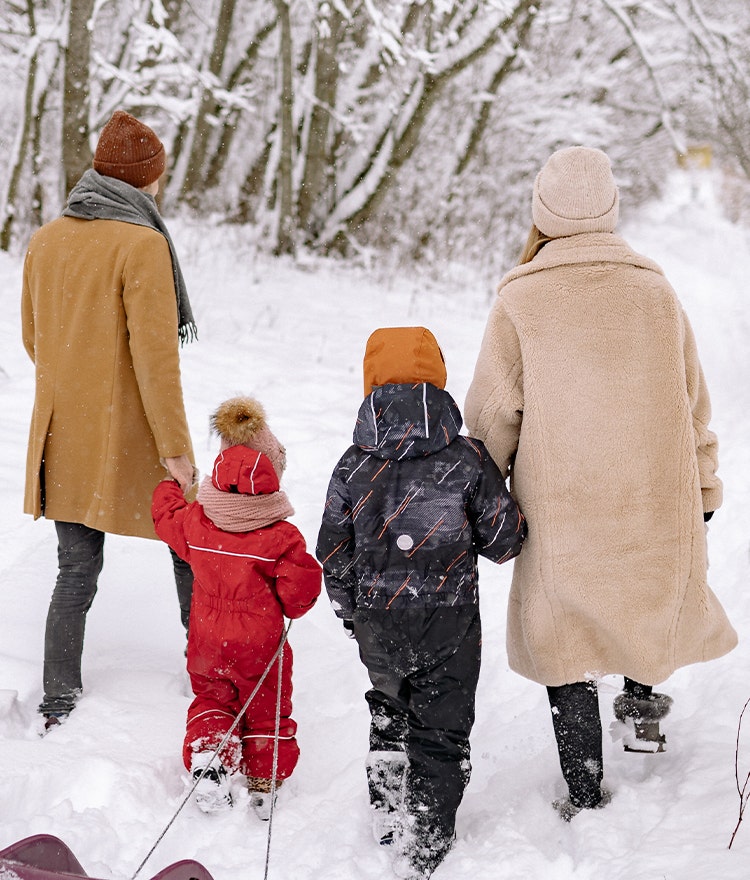 Family of four walking in the snow with their sleds