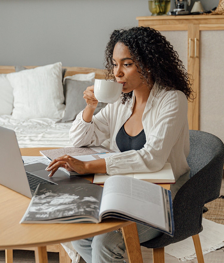 Woman sitting at a table with her laptop and a coffee