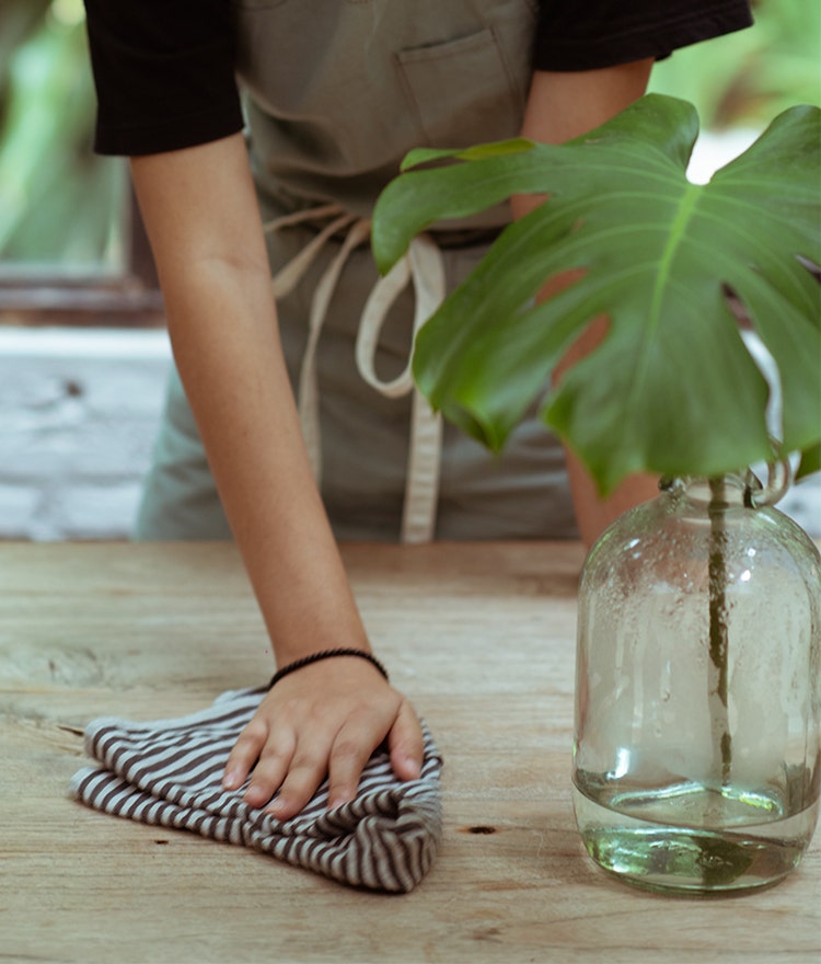 Perspn cleaning a table with a reusable cloth