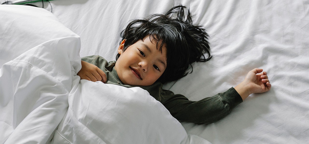 Child smiling and lying down on an organic mattress and sheets