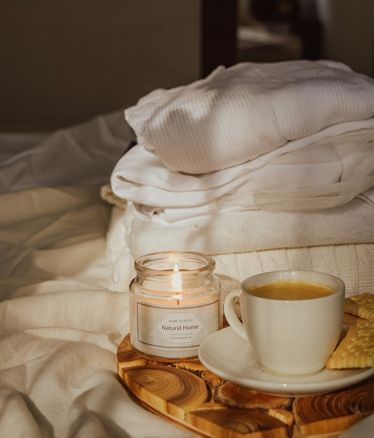 Candle and cup of coffee on a tray near the bed