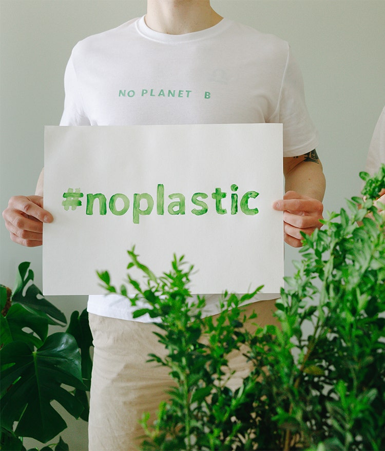 Man holding a sign that says #noplastic