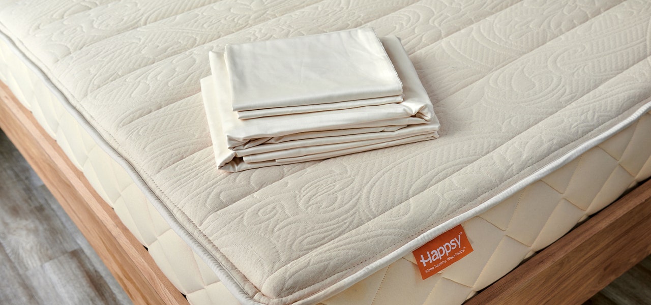 Happsy organic cotton sheets folded on top of mattress