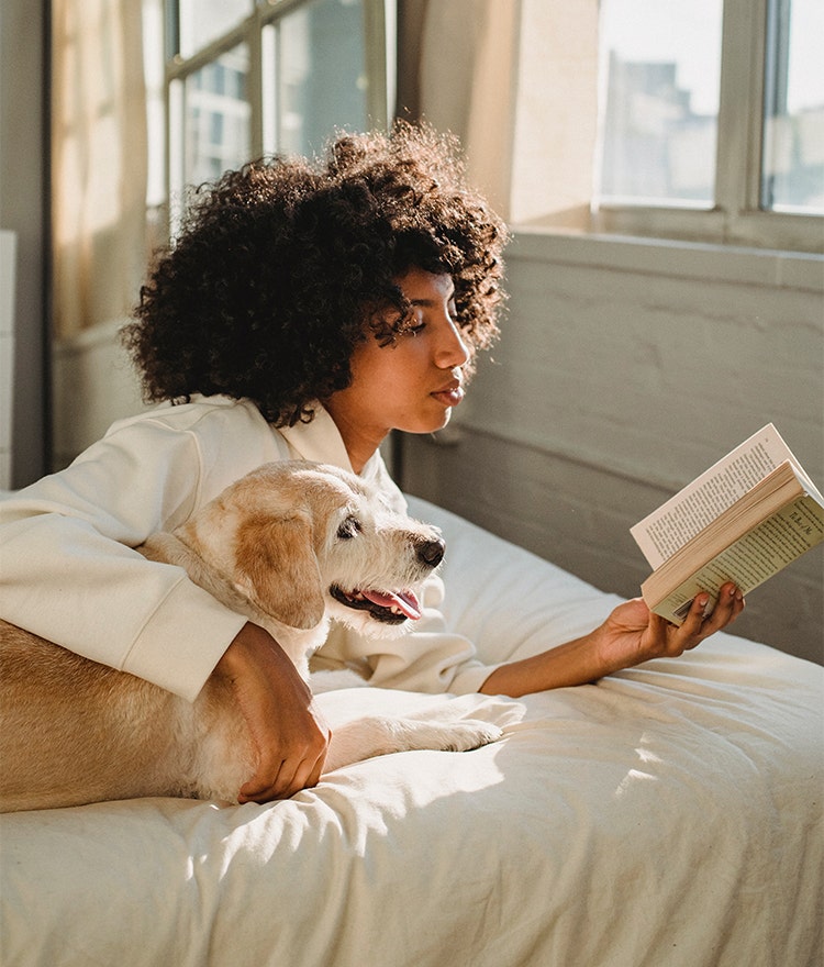 Woman reading in bed with her dog