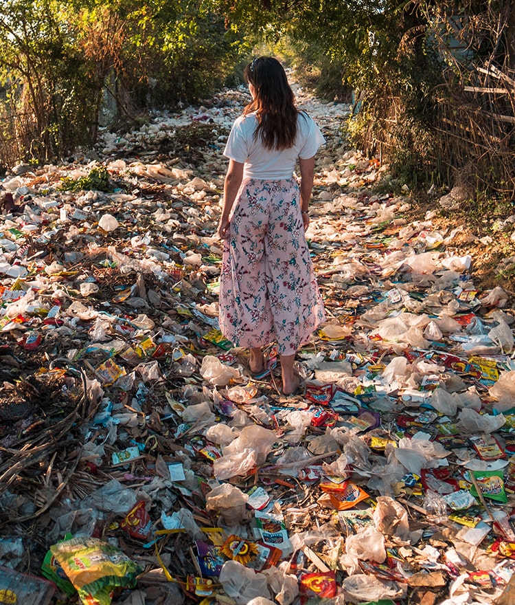 Woman walking in the forest but there is plastic trash everywhere