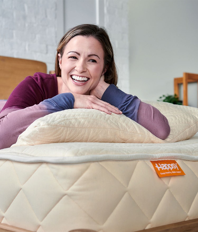 Smiling woman relaxing on her Happsy organic mattress