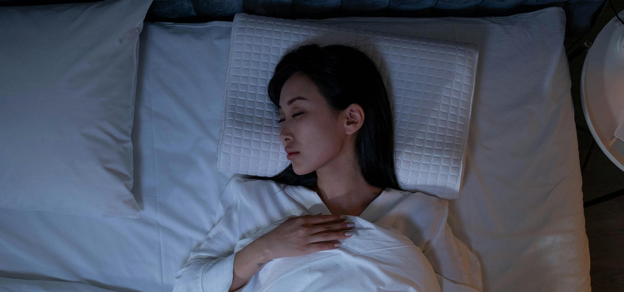 person sleeping on their back in bed at night